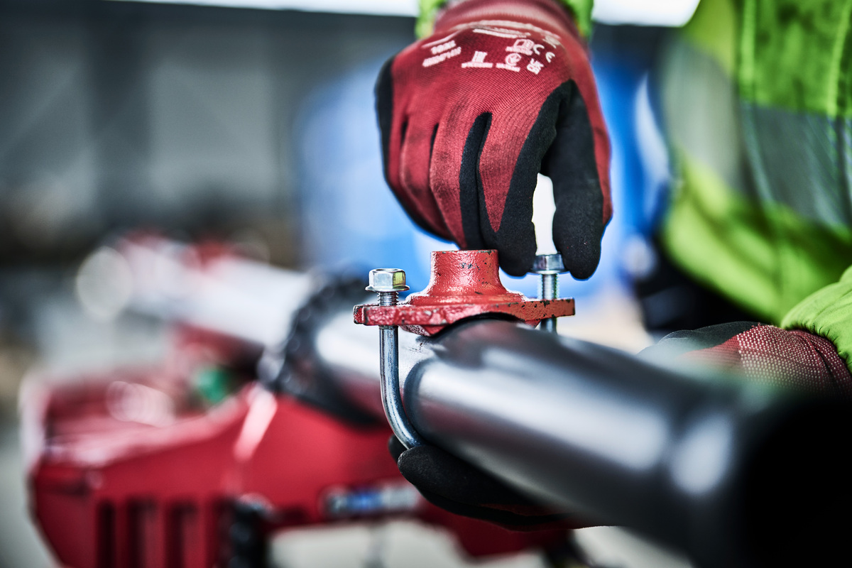 Rørlegger skrur til feste på et rør.